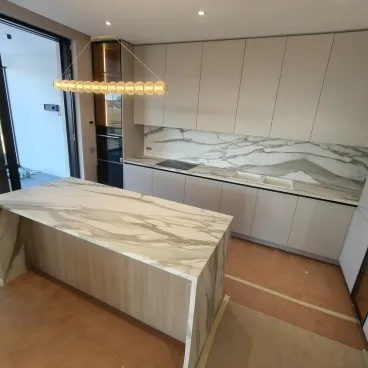 Ceramică Calacatta Gold satinată — bookmatch de la blat la piciorul insulei